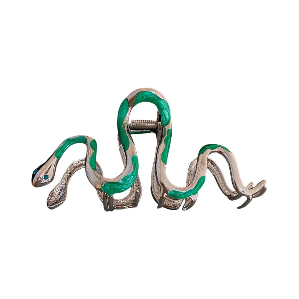 Snake-shaped hair clip with green and silver enamel and blue gemstone eyes.
