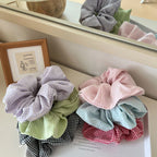Collection of pastel and darker toned gingham scrunchies in a basket
