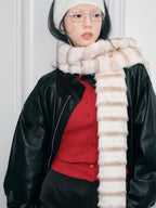 Model wearing a cream and brown striped faux fur scarf and a white ribbed headband, looking at the camera.