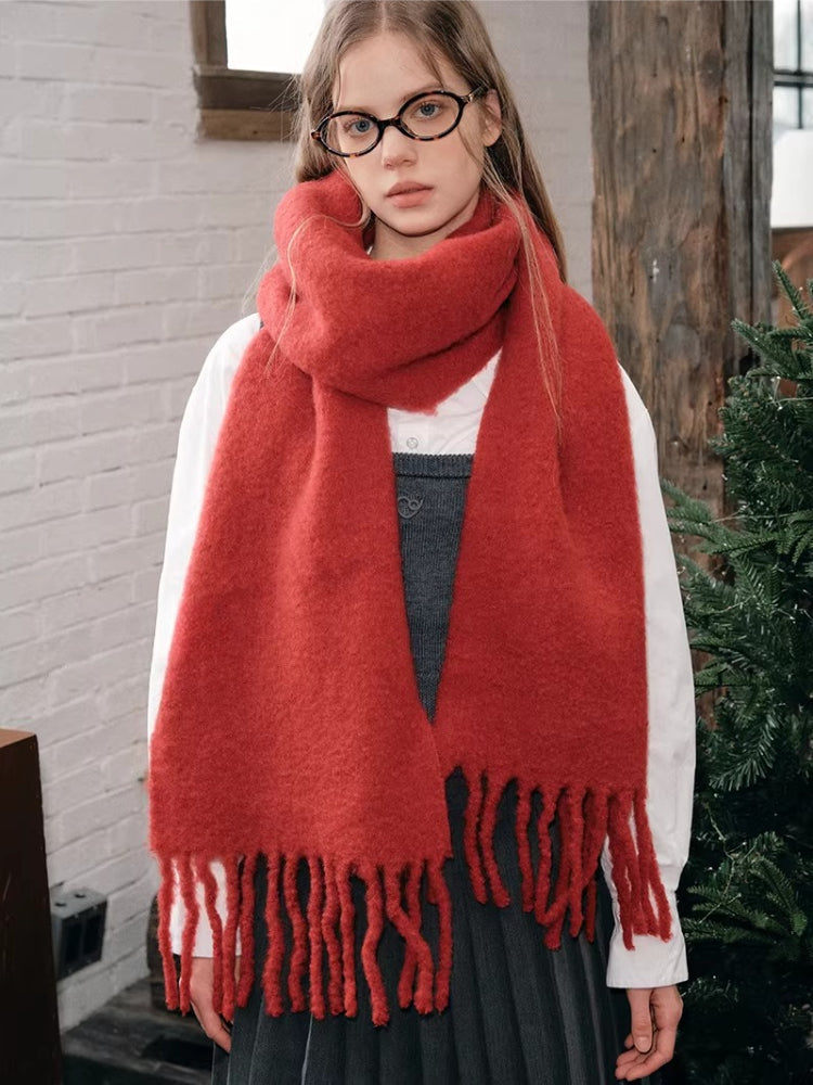 Woman wearing a red oversized scarf with fringed ends
