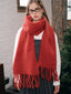 Woman wearing a red oversized scarf with fringed ends