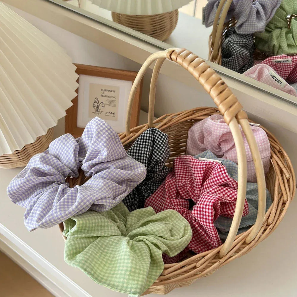 Gingham scrunchies in a wicker basket with a framed picture and lamp in the background