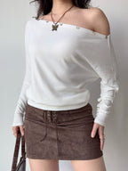 Woman wearing a white off-the-shoulder knit top and a brown suede skirt.