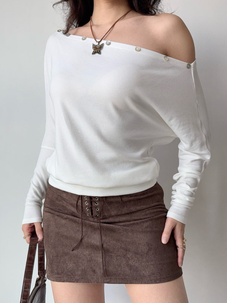 Woman wearing a white off-the-shoulder knit top and a brown suede skirt.