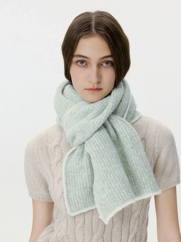 Woman looking forward, wearing a light green ribbed knit scarf with white trim
