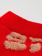 Close-up of the ribbed collar and embroidered detail on a red dog sweater.