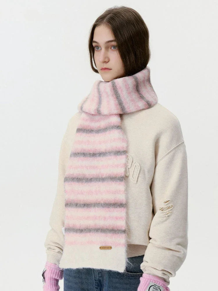Side profile of a woman wearing a pink and grey striped fuzzy scarf