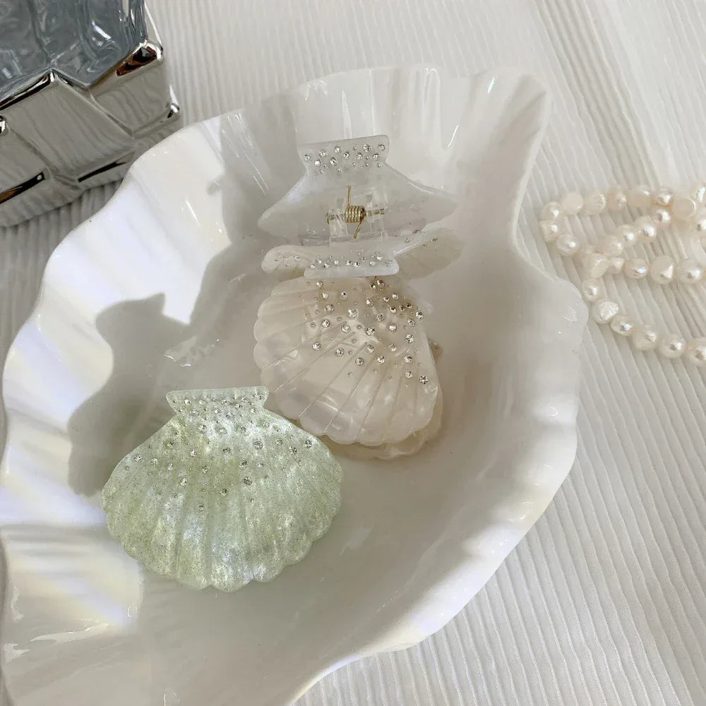 two seashell hair clips with rhinestones in a decorative shell dish