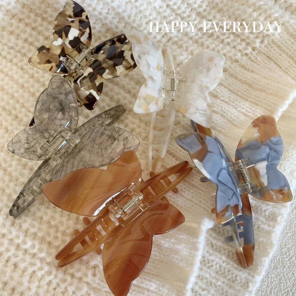 Several butterfly hair claw clips arranged on a textured white surface
