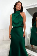 woman wearing a green satin halter neck midi dress in a dressing room