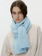 Model wearing a cream sweatshirt and a thick light blue knit scarf wrapped around her neck, front view.