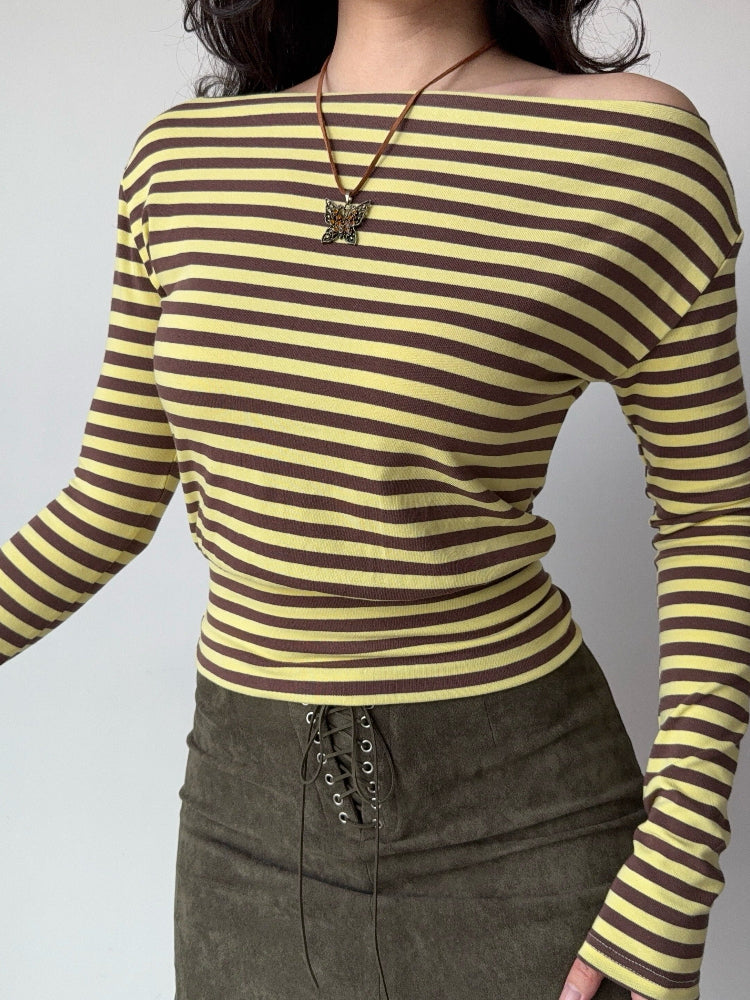 Woman wearing a yellow and brown striped off-the-shoulder long-sleeve top with a brown lace-up mini skirt.