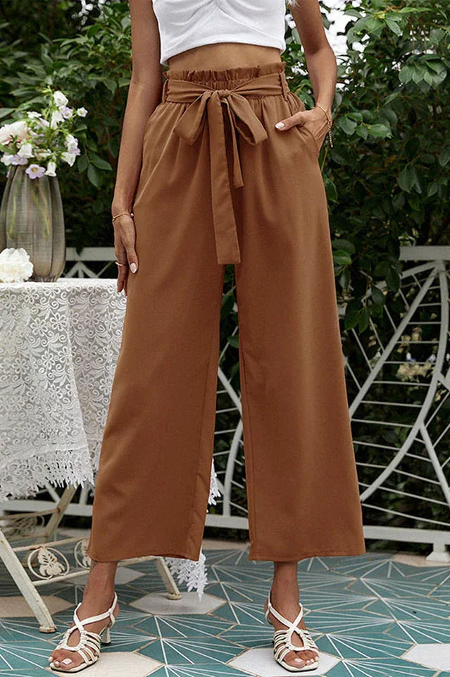Close-up of rust-colored wide-leg pants with a paperbag waist and tie belt.