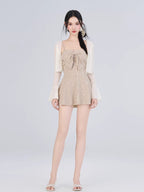 Full body shot of a woman in a striped one-piece outfit and a sheer cardigan.