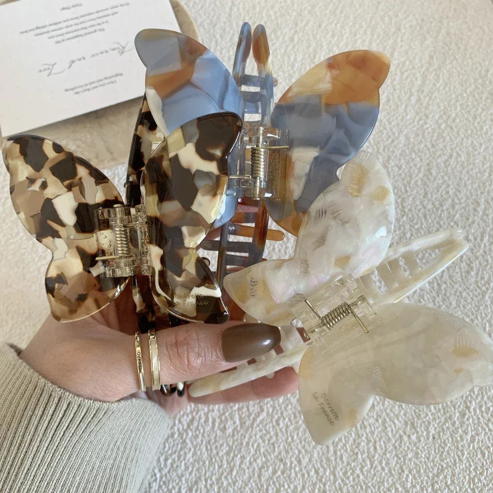 A hand holding a selection of colorful butterfly hair claw clips