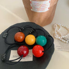 Five colorful ball hair ties on a black surface