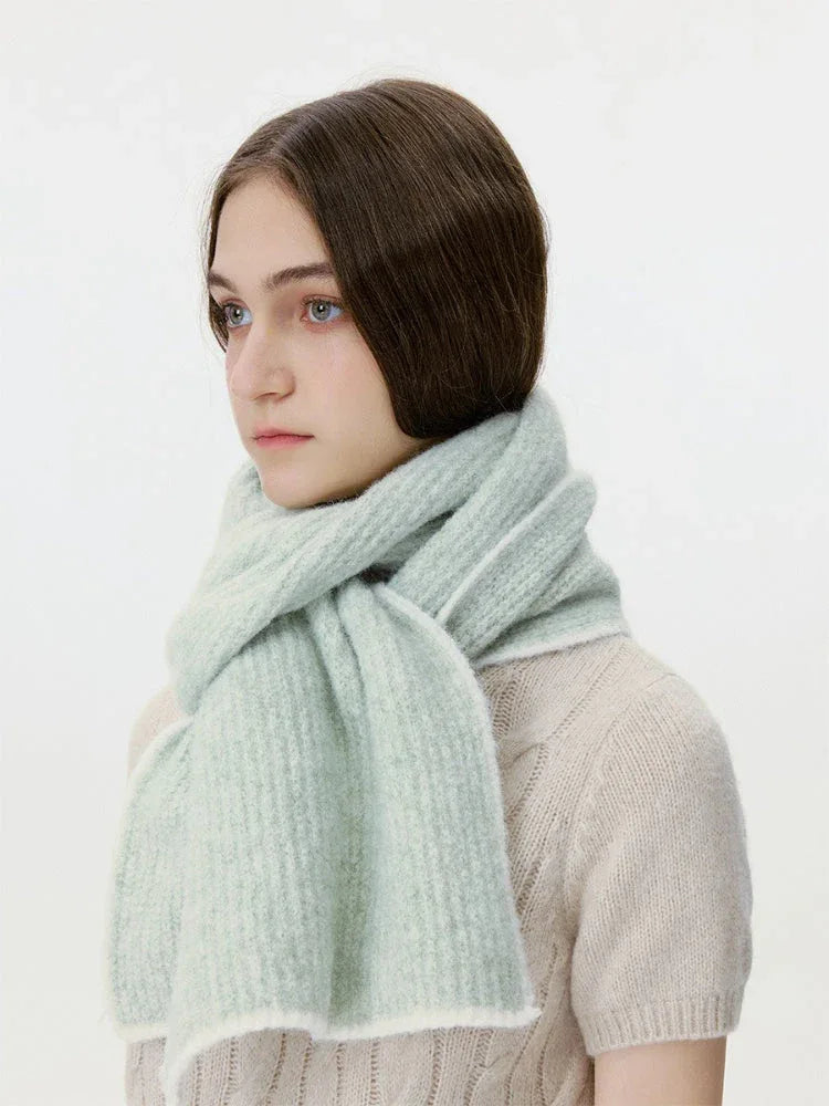 Woman wearing a light green ribbed knit scarf with white trim