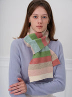 Woman wearing a blue sweater and a pastel striped scarf