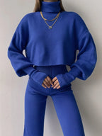 Front view of a woman in a blue knit two-piece set, showing the cropped turtleneck sweater and high-waisted wide leg pants.