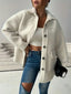 Woman wearing an oversized white sherpa fleece jacket over a white crop top and ripped blue jeans.