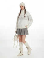 Full-body shot of a model in a winter-themed outfit, including a patterned sweater, pleated skirt, and tall socks.