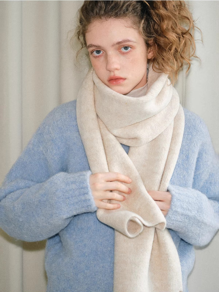 Model wearing a light blue knit sweater and a cream scarf.