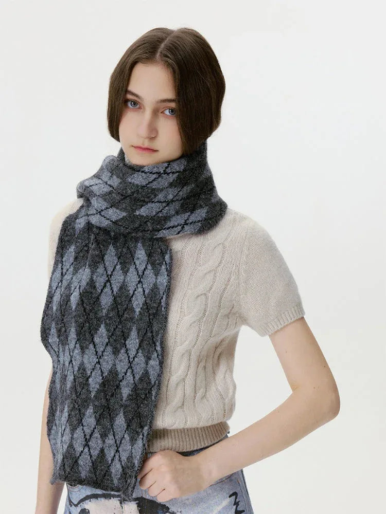Woman posing with a cream cable-knit sweater and a grey and black argyle scarf
