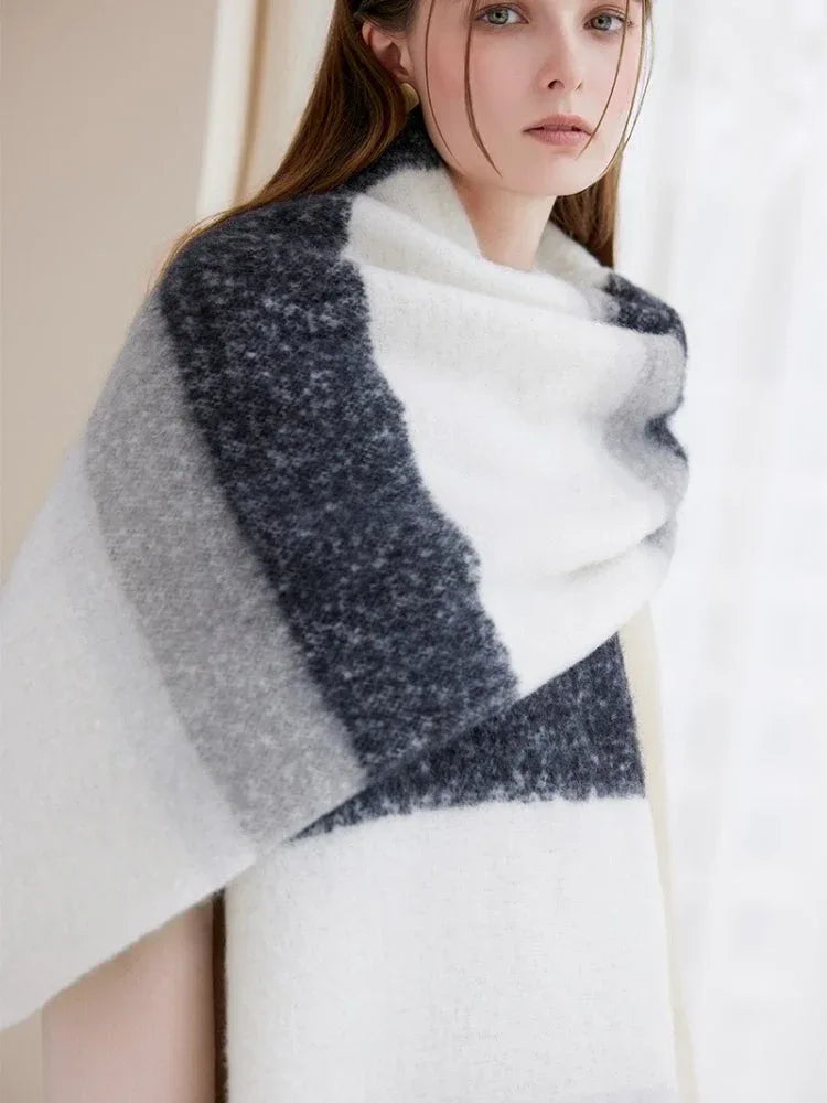 Detailed view of an oversized striped scarf with prominent white, grey, and dark blue bands, and a soft, textured knit.
