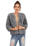 Woman wearing a grey faux fur jacket over a light-colored top and ripped jeans.