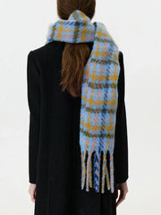 Back view of a woman wearing a black coat and a blue and yellow plaid scarf with fringe