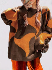 Close-up of a woman wearing a brown and orange abstract patterned oversized sweater.