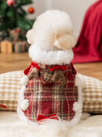 The back of a white bichon frise dog in a red plaid dog coat with faux fur trim and reindeer antlers.