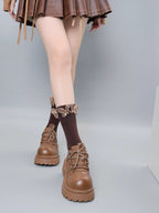 Front view of brown ribbed socks with ruffled butterfly trim and brown lace-up platform shoes, worn with a brown skirt.