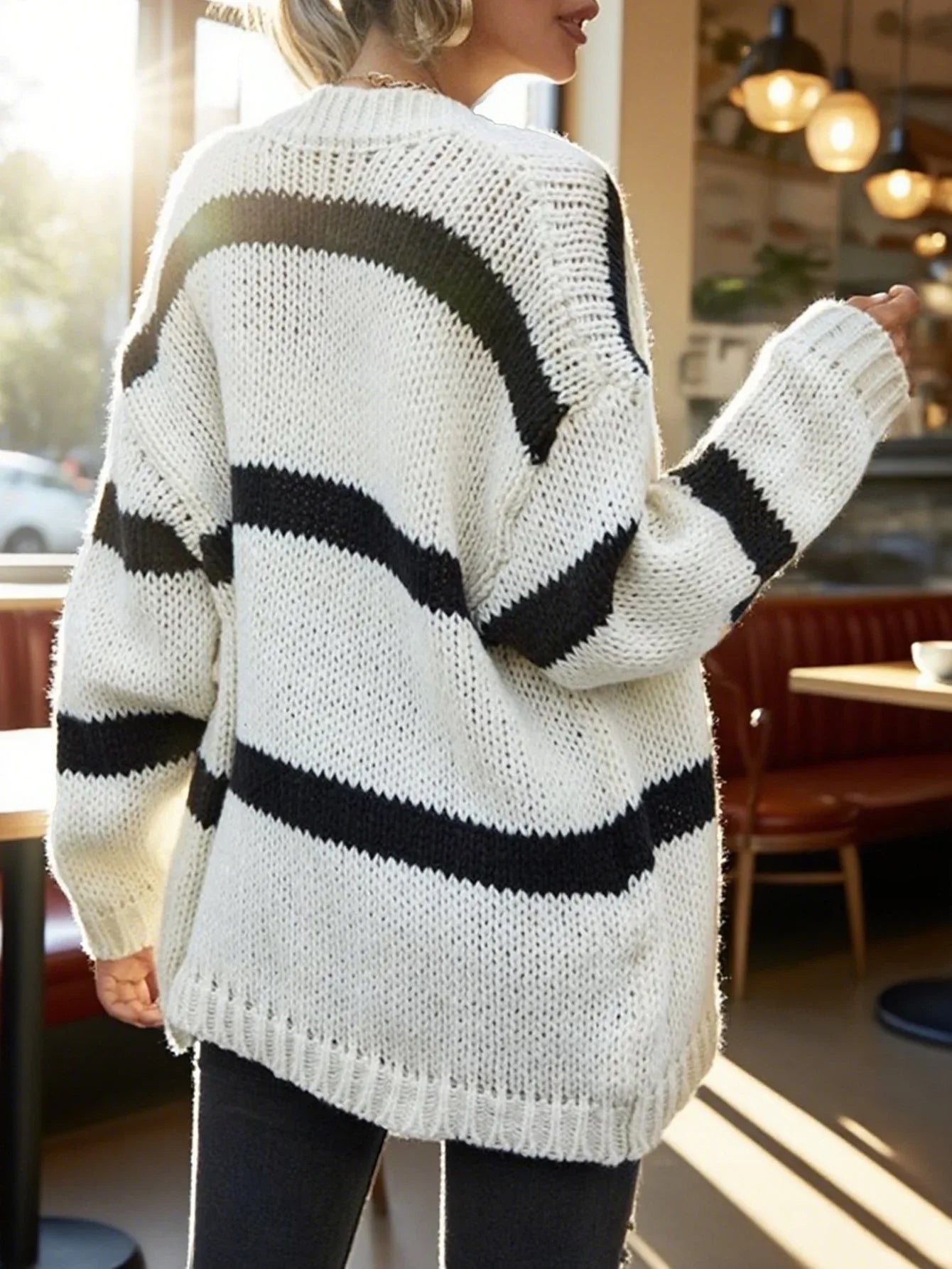 Back view of a woman in a white and black striped knit cardigan.