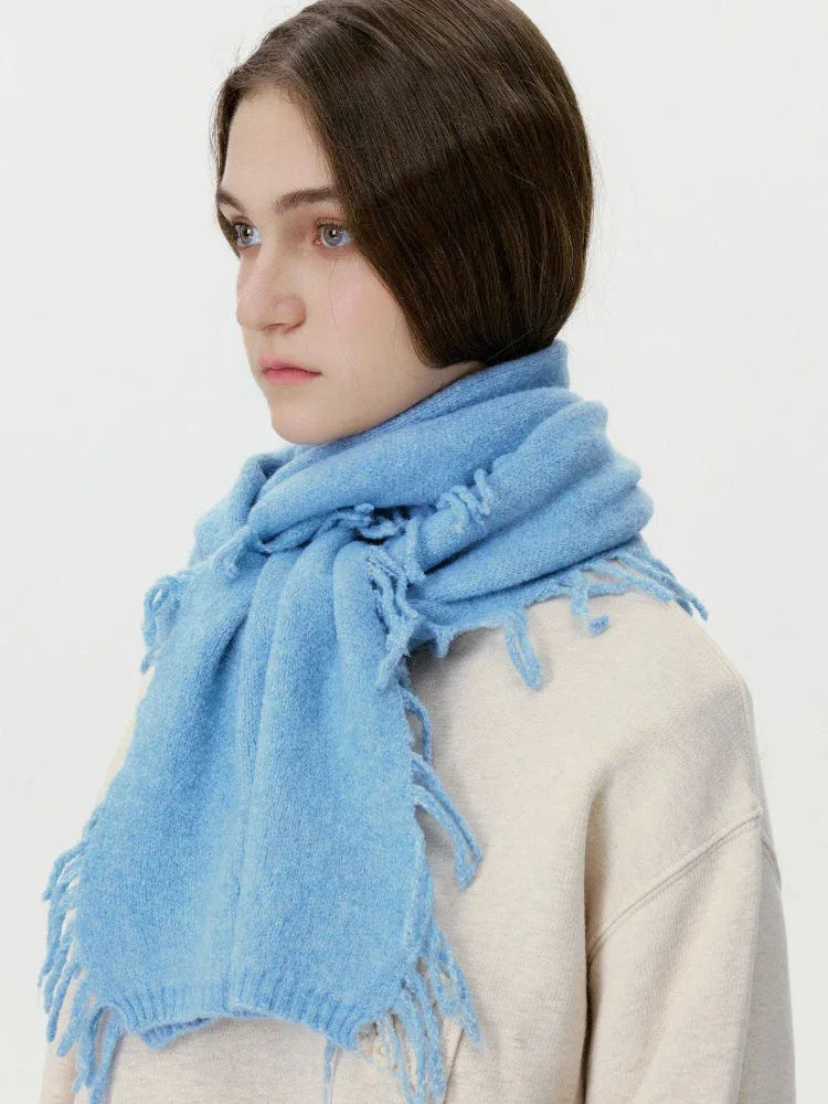 Side profile of a woman wearing a light blue knitted scarf.