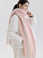 Woman wearing a pink and purple striped scarf with fringe detail over a white puffer jacket, side view