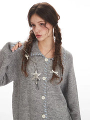 Close-up of a model wearing a grey knitted cardigan, focusing on the necklace and hair accessories.