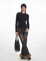 Model in a black ribbed knit top and distressed flared jeans with fur trim cuffs, with hands in pockets.