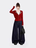 Woman posing in a red knit cardigan, white t-shirt, and dark wash wide-leg jeans, with a black backpack