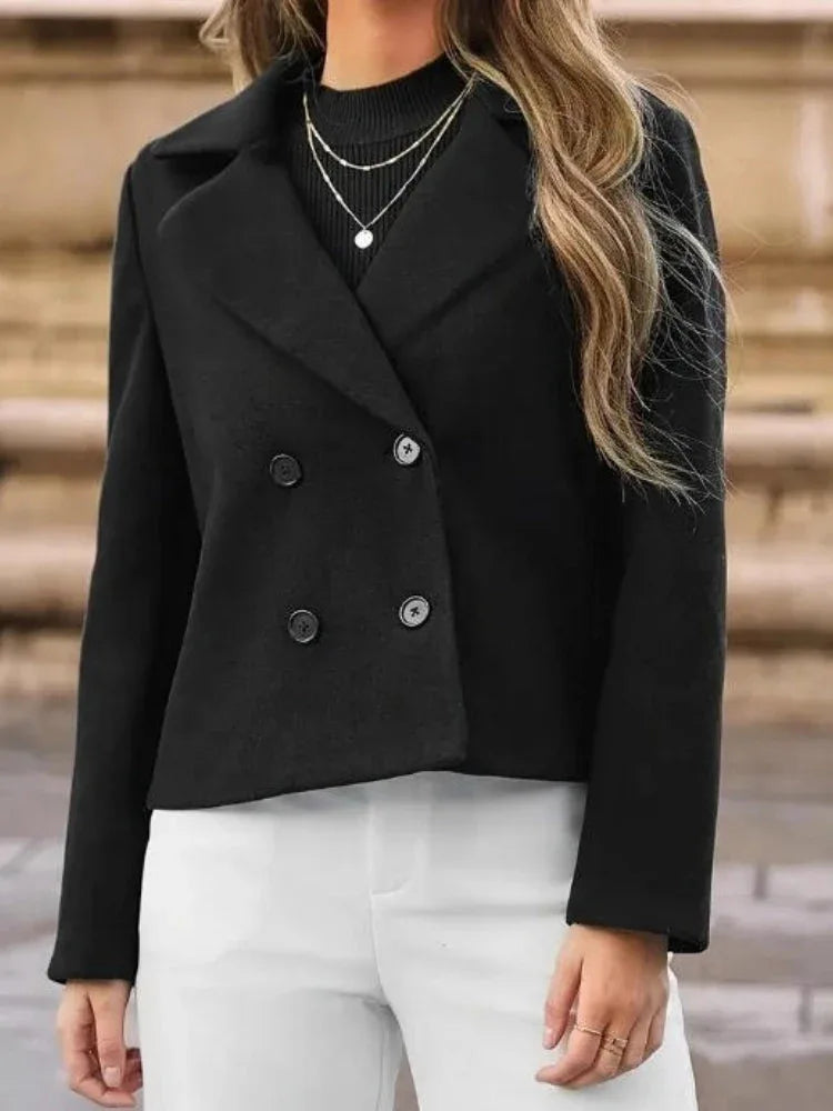 Woman wearing a black double-breasted cropped jacket with white pants Main image