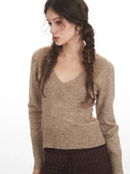 Close-up front view of a woman wearing a beige V-neck sweater.