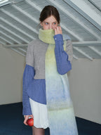 Close-up of a woman wearing an oversized ombre scarf, obscuring her mouth.