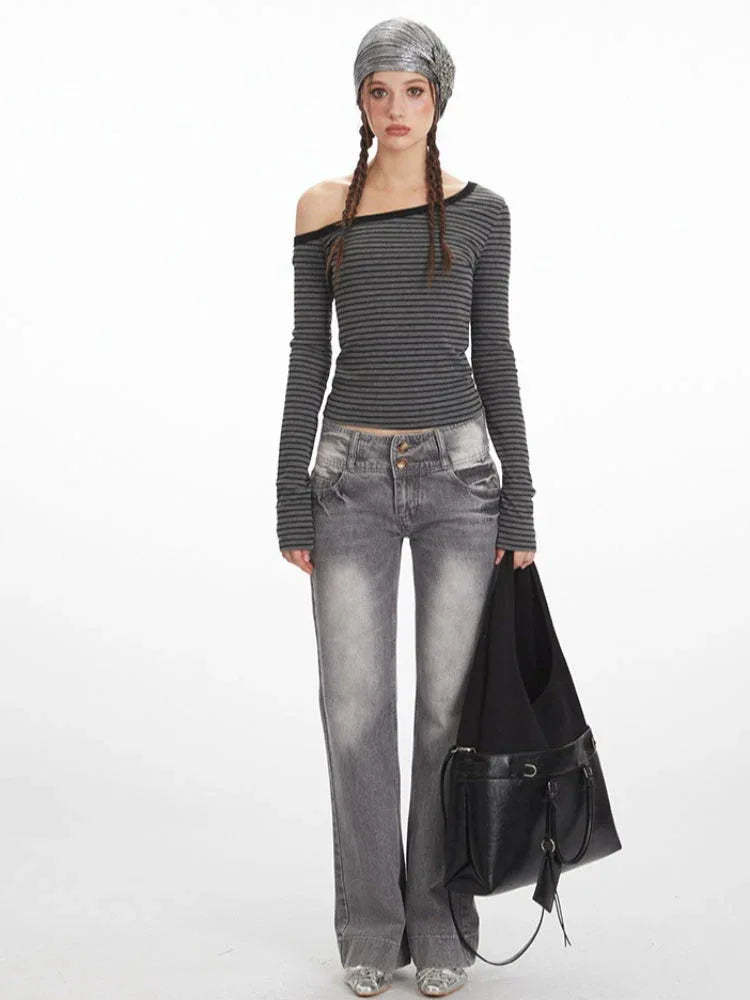 Woman wearing a grey and black striped off-the-shoulder long-sleeve top and grey wide-leg jeans, holding a black shoulder bag.