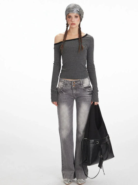 Woman wearing a grey and black striped off-the-shoulder long-sleeve top and grey wide-leg jeans, holding a black shoulder bag.
