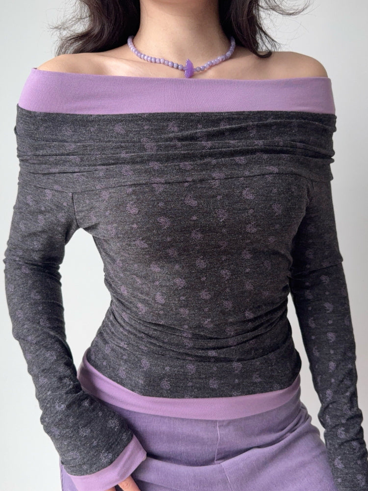 Side view of a woman wearing a grey and purple off-the-shoulder long-sleeve top with ruching.