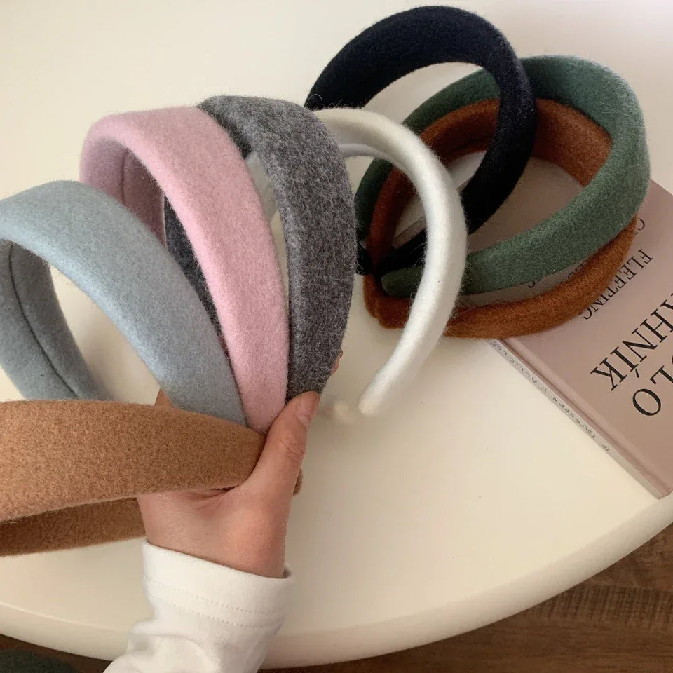 Assortment of padded felt headbands in various colors held by a hand Secondary image