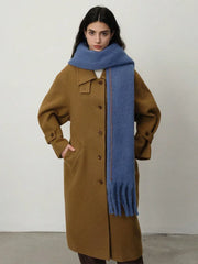 Full-body shot of a woman in a brown coat and a blue scarf