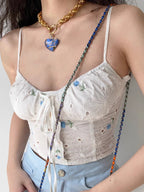 Side view showing the adjustable spaghetti strap and eyelet texture of the white cropped top.
