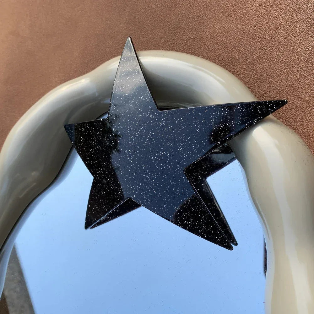 black glitter star hair clip attached to a decorative mirror frame