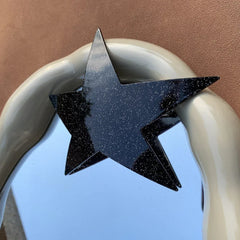 black glitter star hair clip attached to a decorative mirror frame